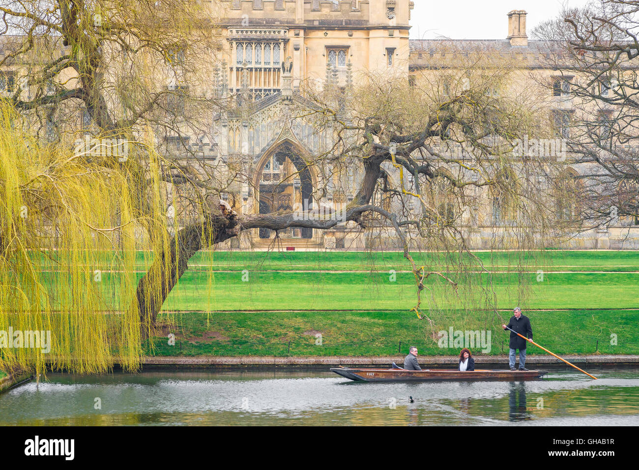 On an early spring morning in Cambridge, UK, tourists take a trip in a punt on the River Cam, gliding past St Johns College. Stock Photo