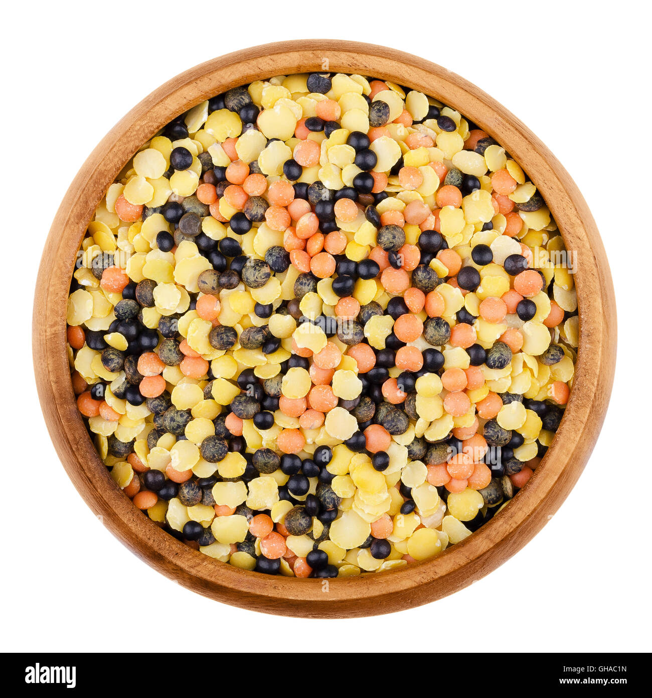 Mixed lentils in a wooden bowl on white background. Yellow, green, red and black beluga lentils. Stock Photo