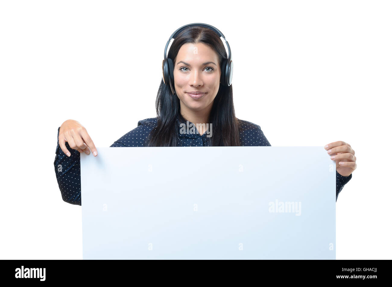 Young woman wearing a headset holding a blank white rectangular sign board or placard with copy space in front of her chest, iso Stock Photo