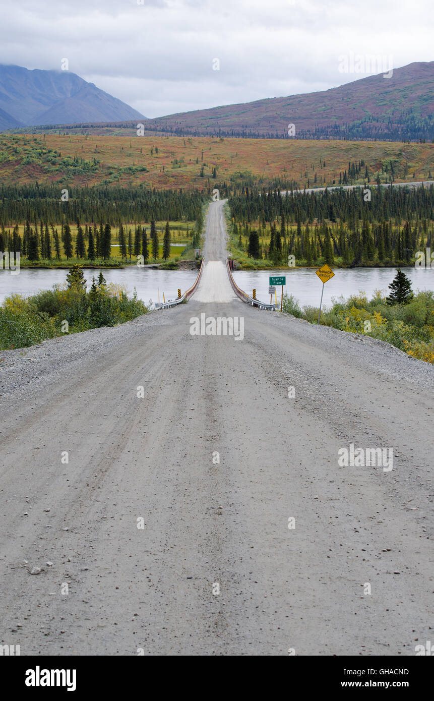 The gravel Denali highway leads down to the bridge crossing the Sustna
