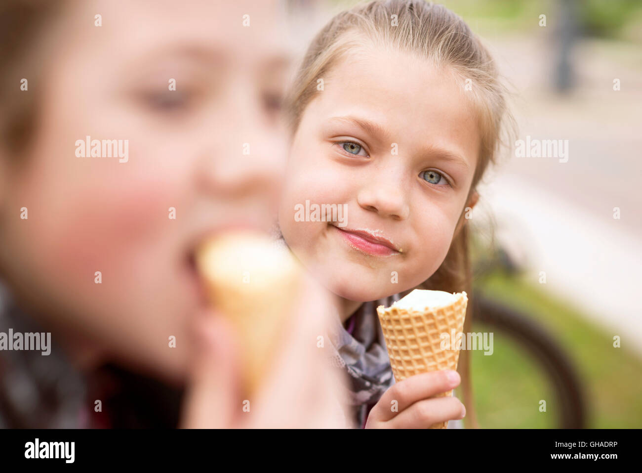 two girls enjoy ice-cream eating outdoor by summer Stock Photo