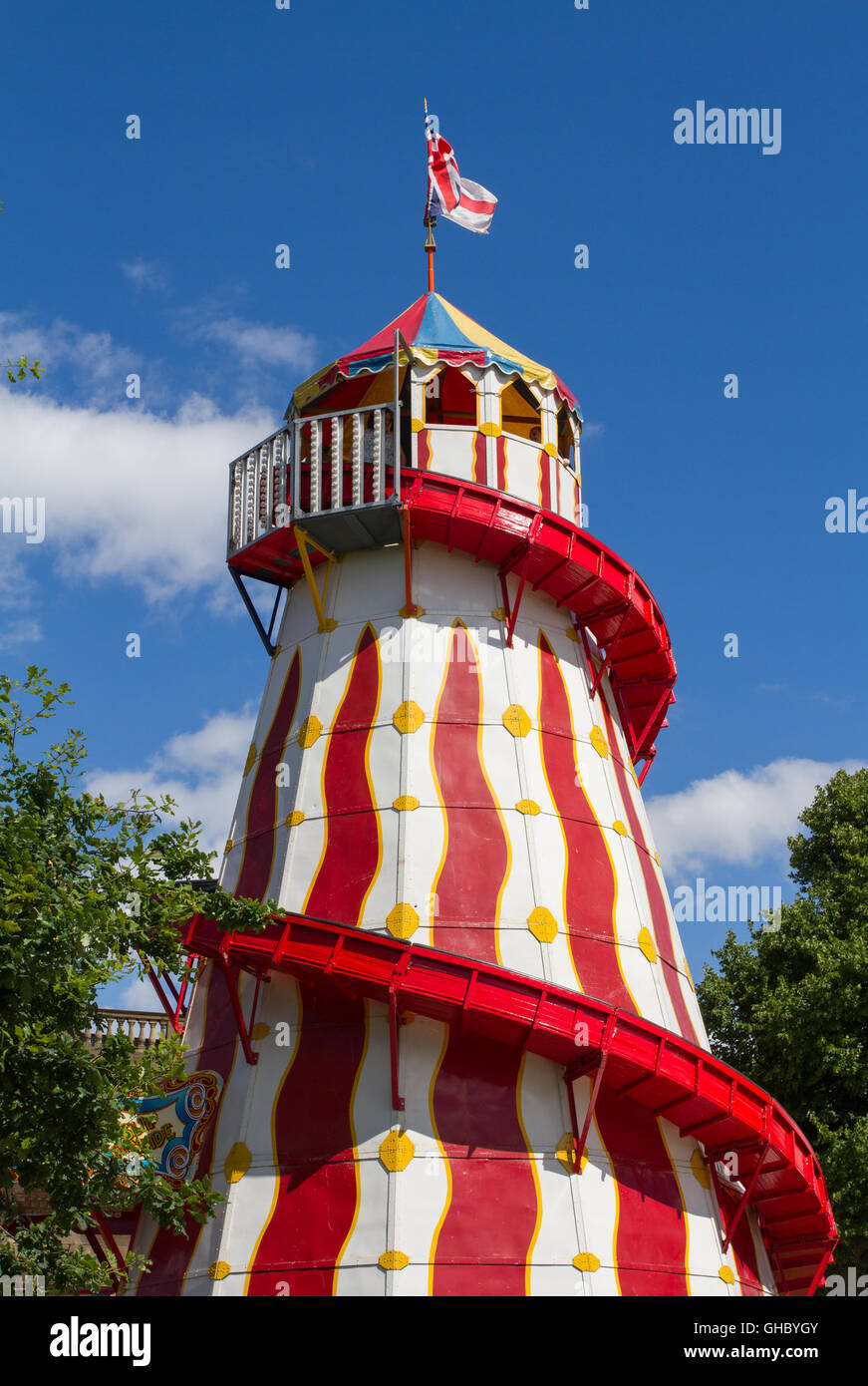 The colorful, tall structure of a Helter Skelter slide at a funfair or fairground under a bright, blue sky. Stock Photo