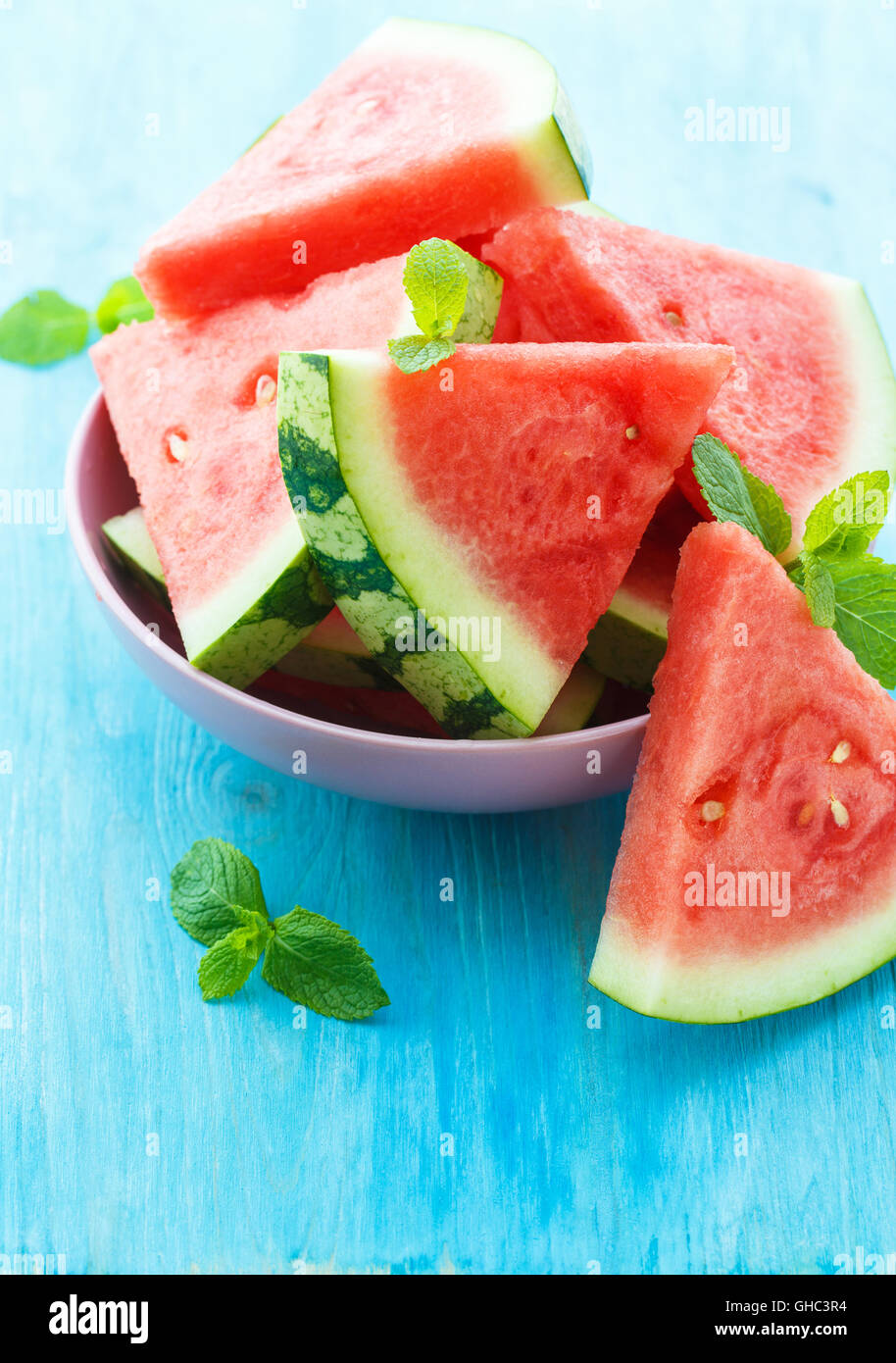 Triangular slices of fresh watermelon with mint on blue wooden background Stock Photo