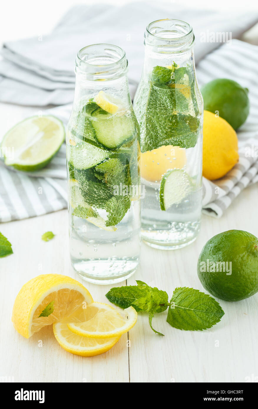 Infused water with citrus and mint in glass bottles on white wooden background Stock Photo