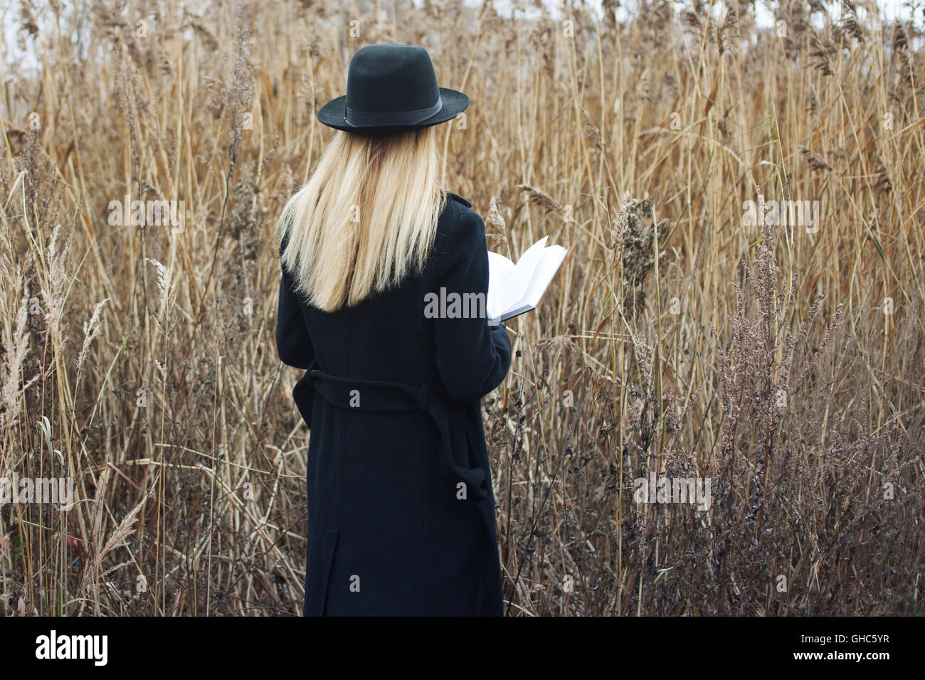 Portrait of young attractive woman in a black coat and hat. She's one ...