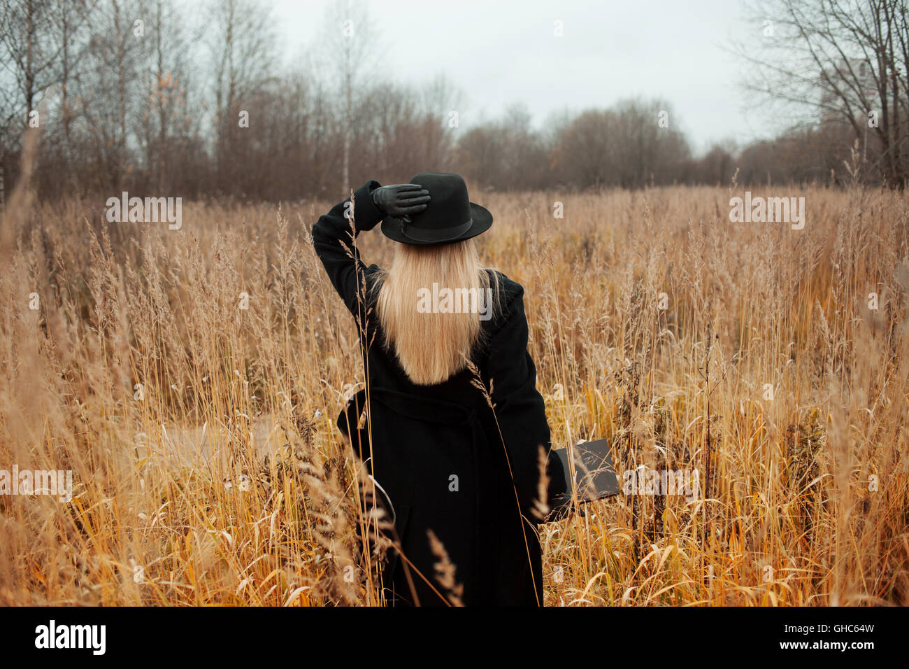Portrait of young attractive woman in a black coat and hat. She's one ...