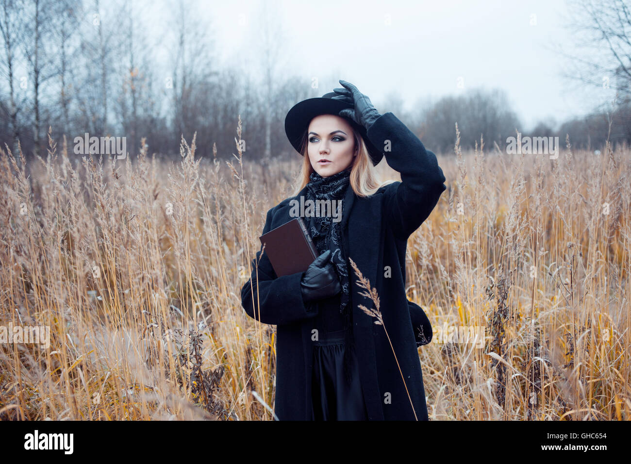 Portrait of young attractive woman in a black coat and hat. She's one ...