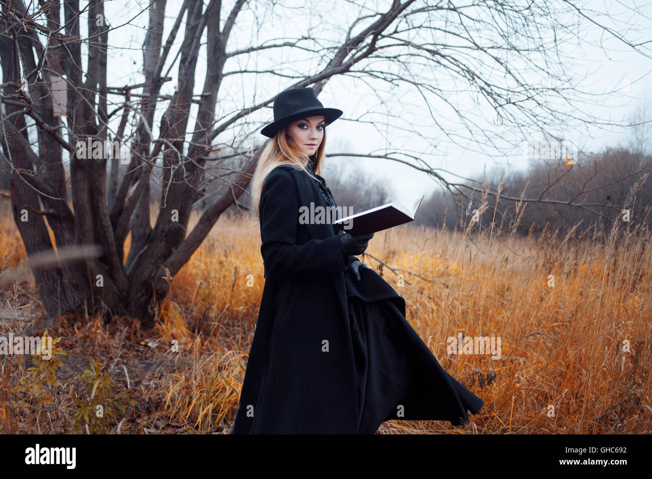 Portrait of young attractive woman in a black coat and hat. She's one ...