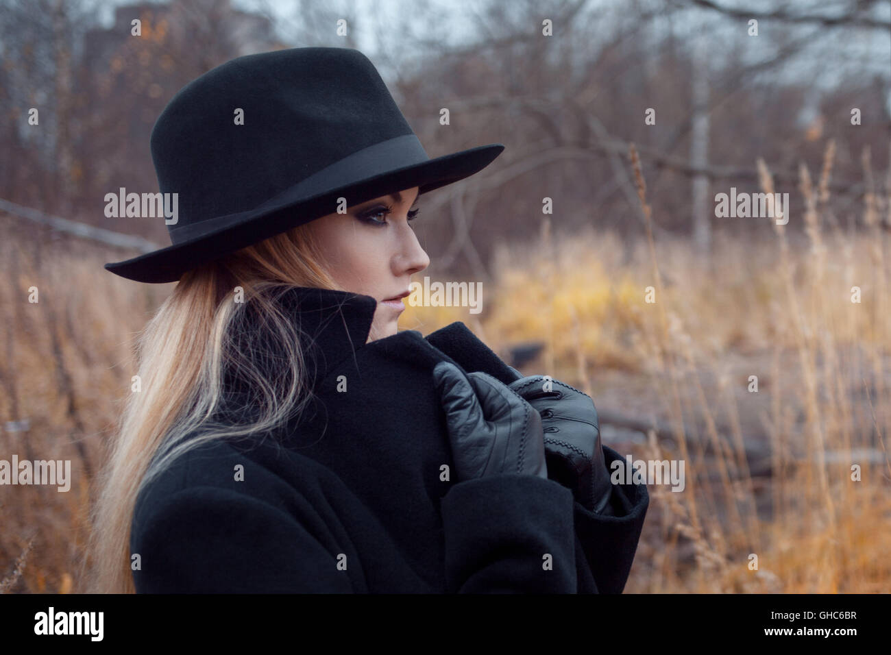 Portrait of young attractive woman in a black coat and hat. She's one ...