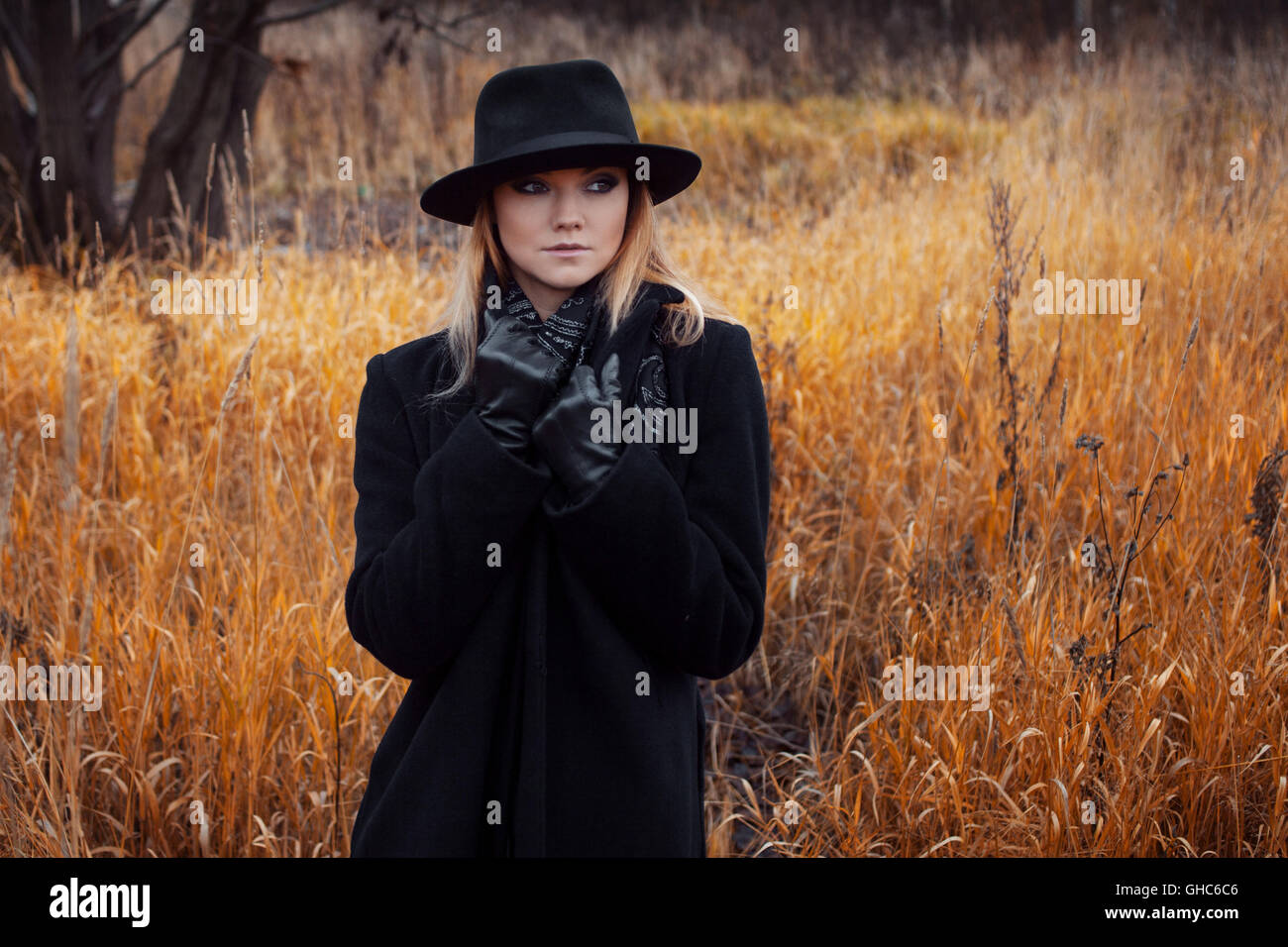 Portrait of young attractive woman in a black coat and hat. She's one ...