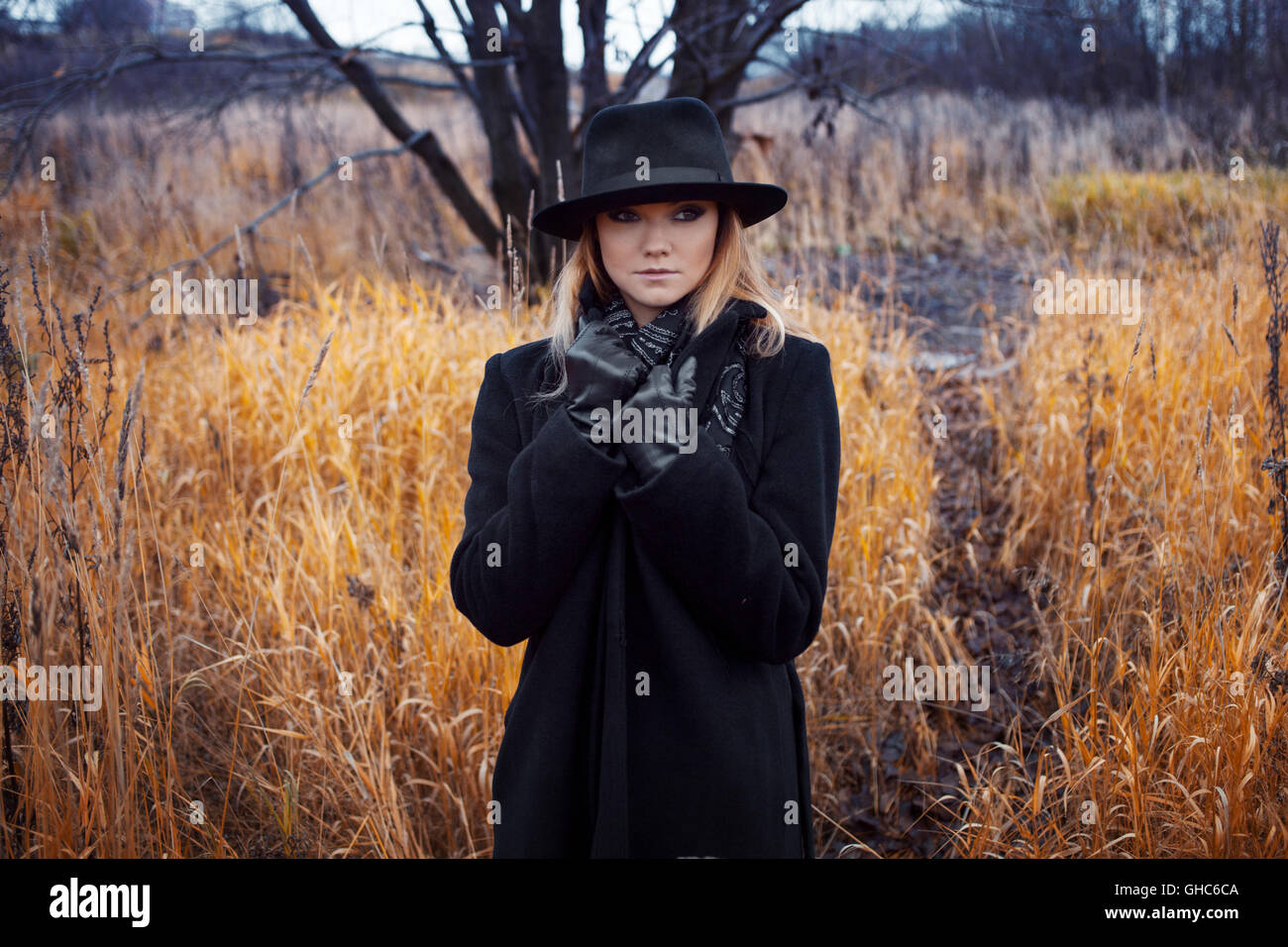 Portrait of young attractive woman in a black coat and hat. She's one ...