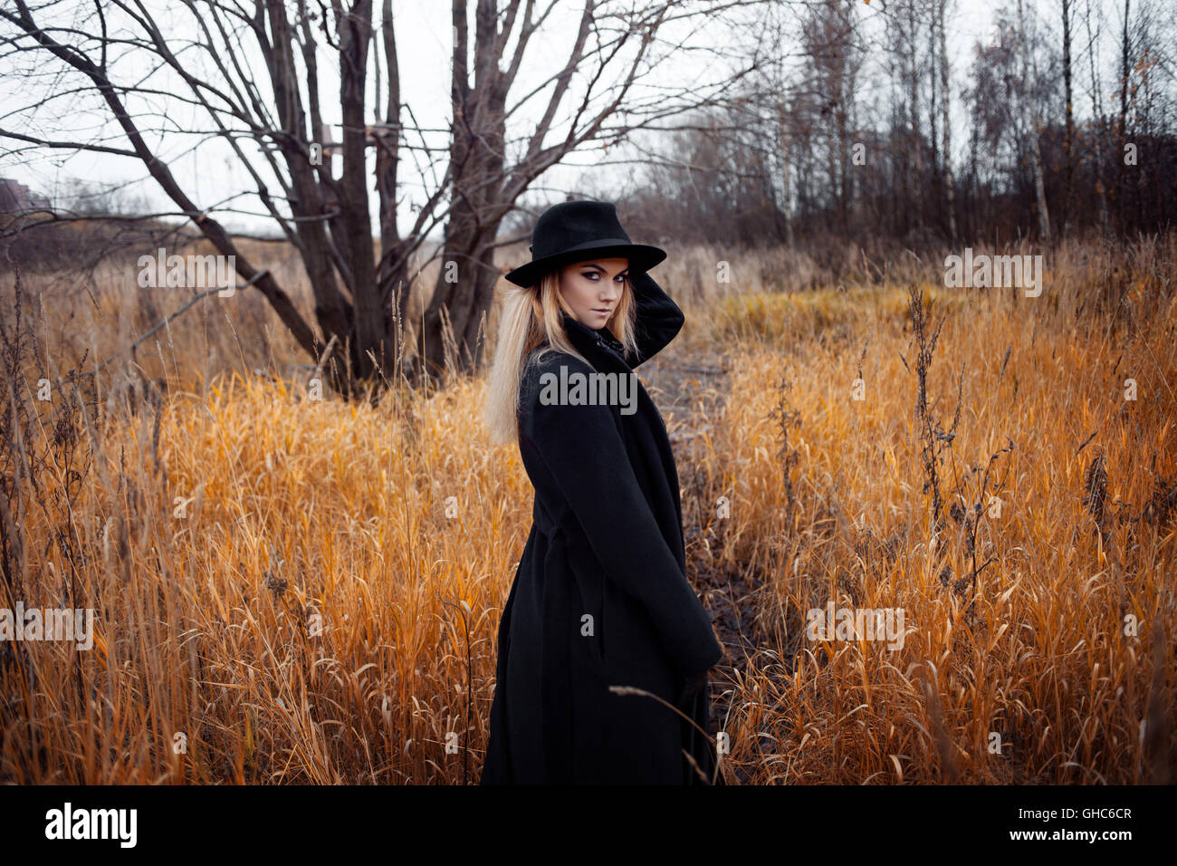 Portrait of young attractive woman in a black coat and hat. She's one ...