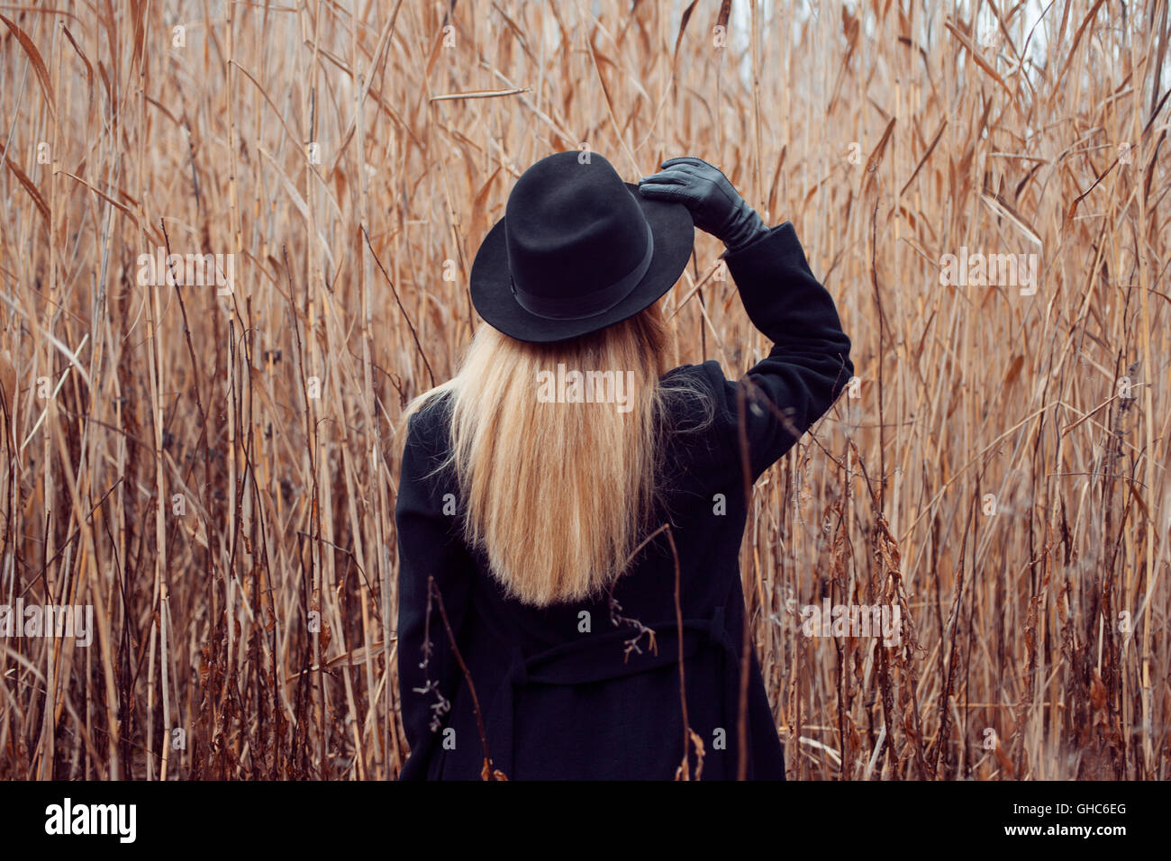 Portrait of young attractive woman in a black coat and hat. She's one ...