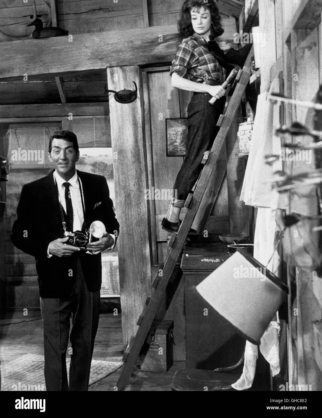 WHAT A WAY TO GO! What a Way to Go USA 1964 J. Lee Thompson Scene: Lennie Crawley (DEAN MARTIN) with camera and Louisa Foster (SHIRLEY MACLAINE) in jeans climbing a ladder Regie: J. Lee Thompson aka. What a Way to Go Stock Photo
