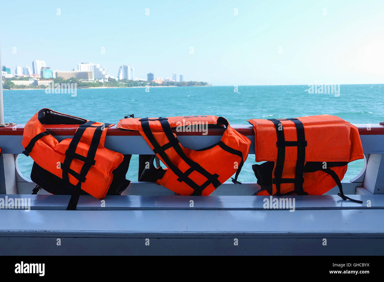 Safety life vests in orange hanging on ferry boat sailing in sea Stock Photo