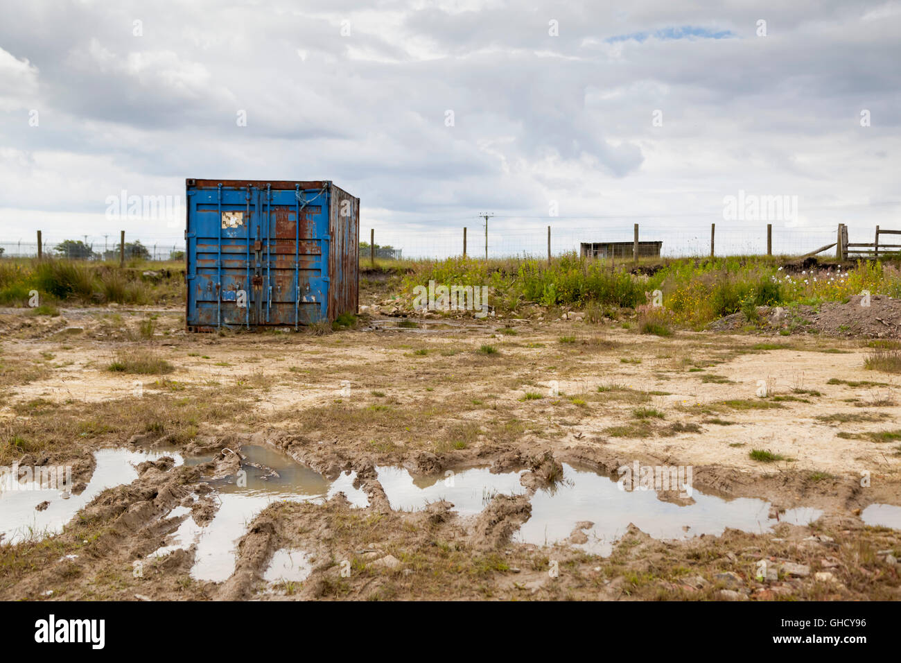 Abandoned shipping container on muddy waste ground Stock Photo