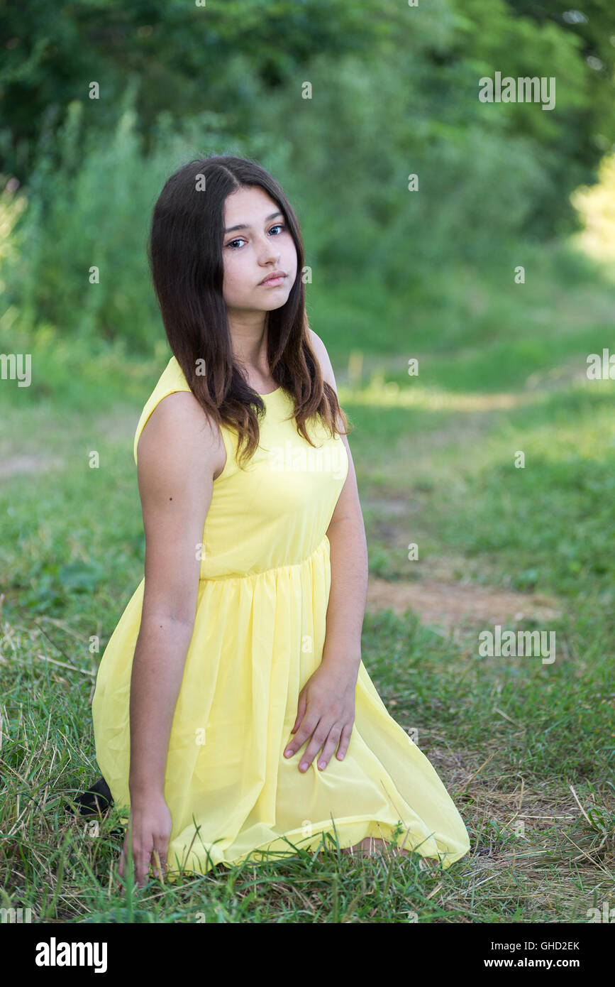 The girl in a yellow dress sitting on the grass Stock Photo - Alamy
