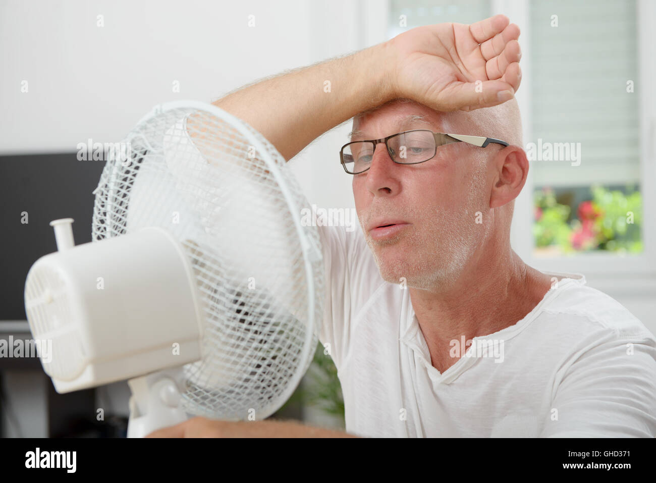 mature man refreshed with a fan in his home Stock Photo