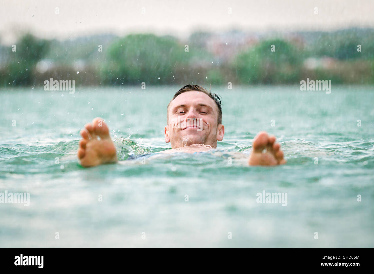 Man swimming in lake under the rain in thunderstorm Stock Photo Alamy