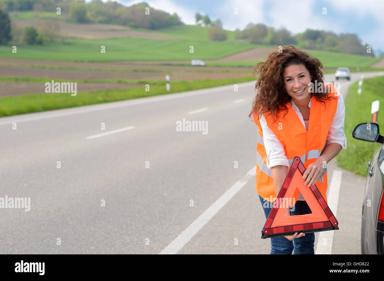 Pretty young woman holding a red triangular traffic warning sign in her ...