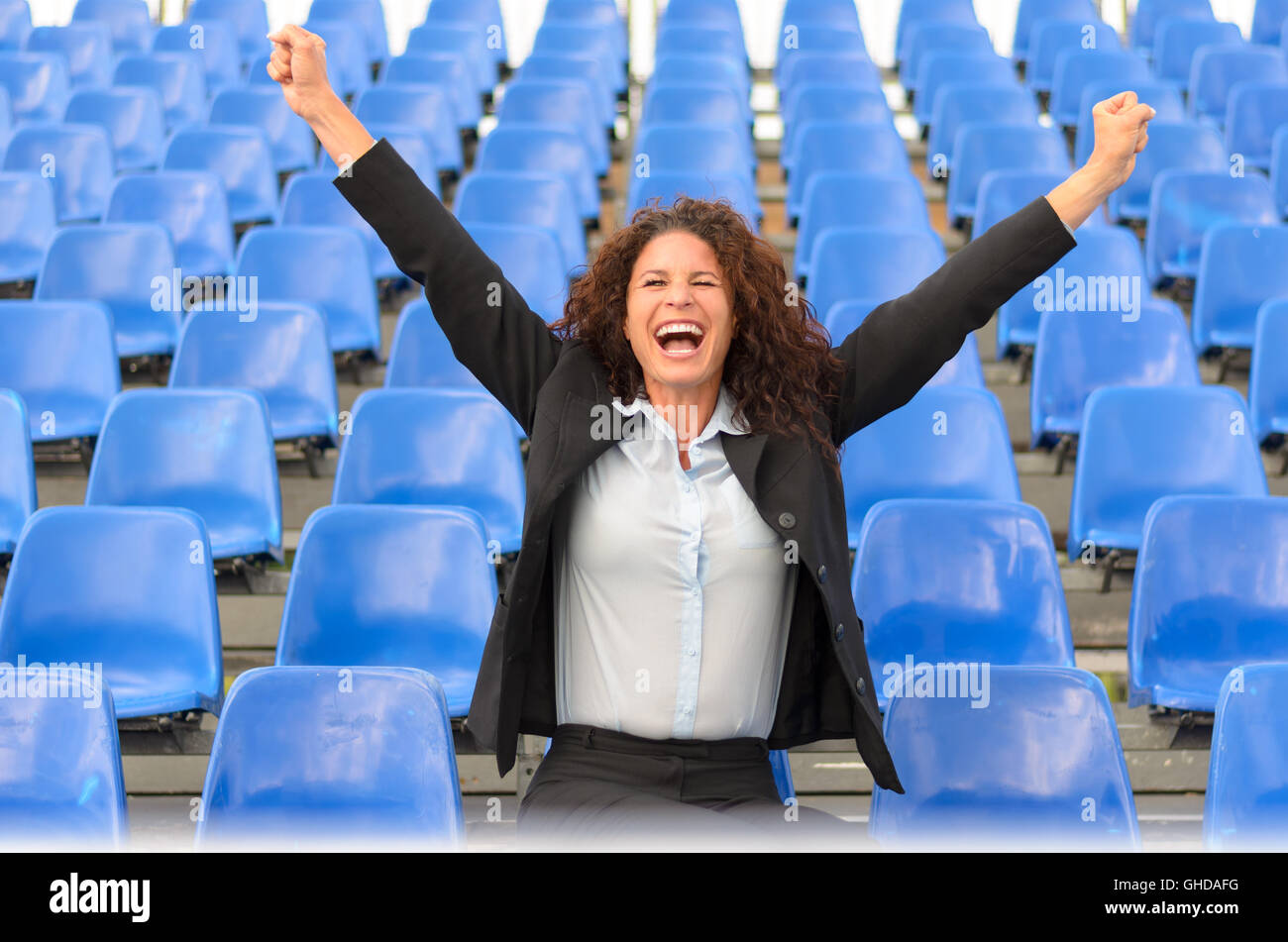 Young attractive female supporter cheering her team as she stands alone