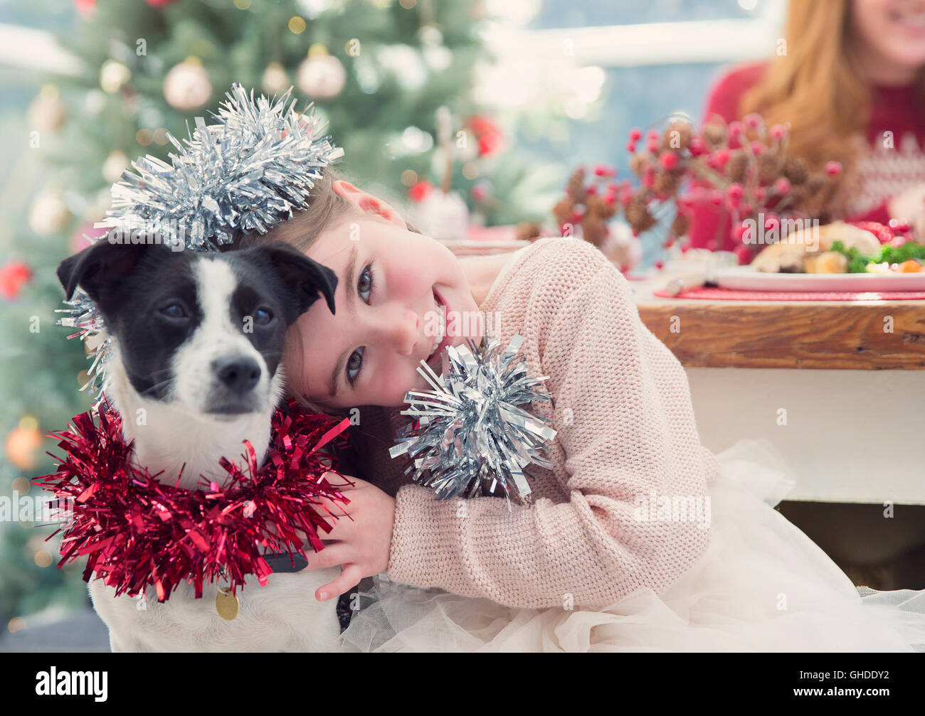 Portrait smiling girl hugging dog with Christmas decoration Stock Photo