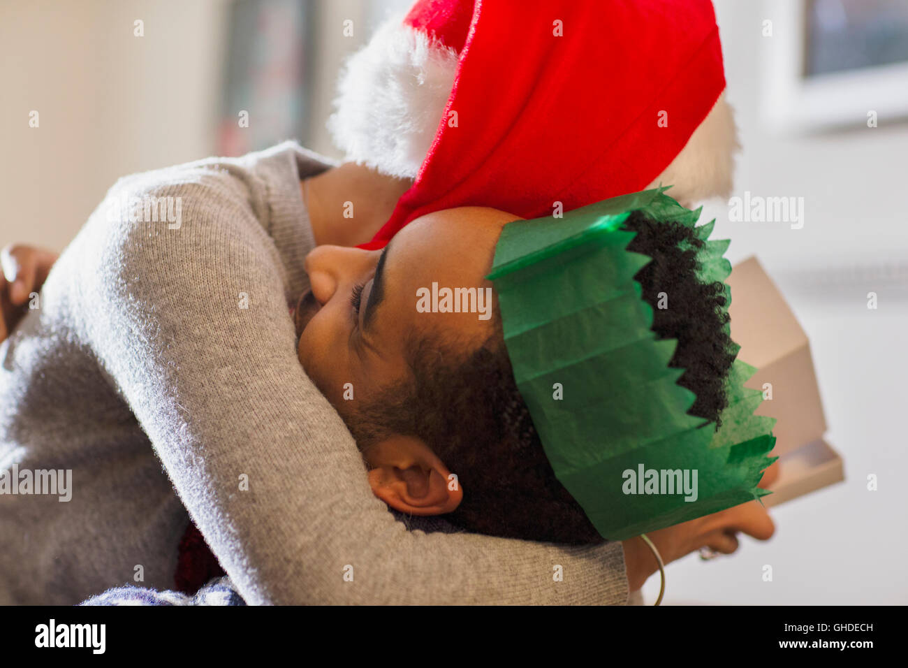Affectionate couple in paper crown and Santa hat hugging Stock Photo