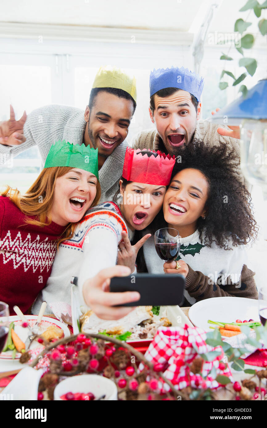 Silly friends in paper crowns taking selfie at Christmas dinner Stock Photo