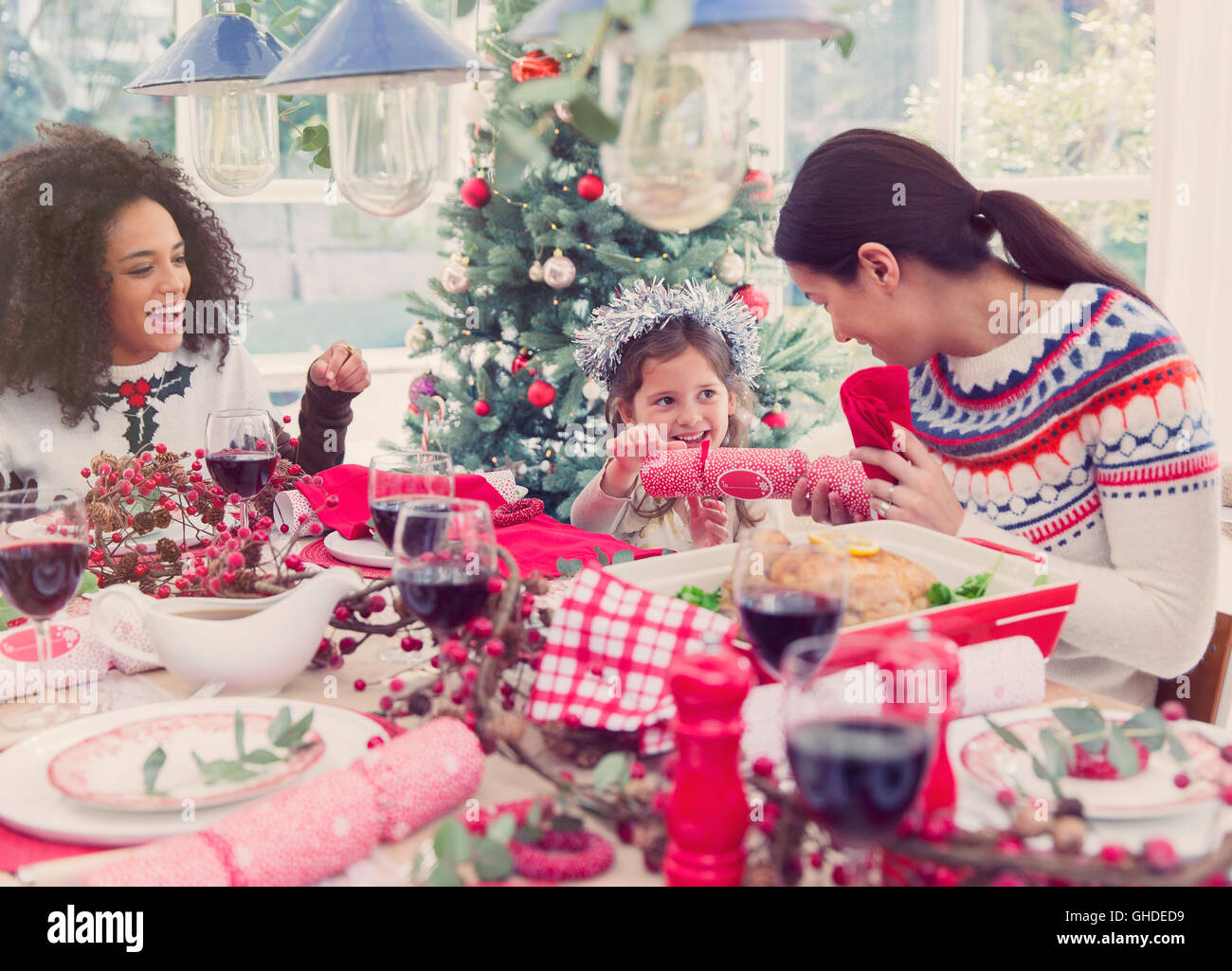 Mother and daughter pulling Christmas cracker at dinner Stock Photo