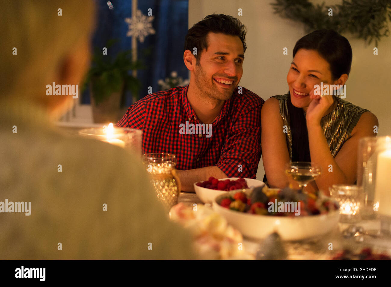 Smiling couple enjoying candlelight Christmas dinner Stock Photo
