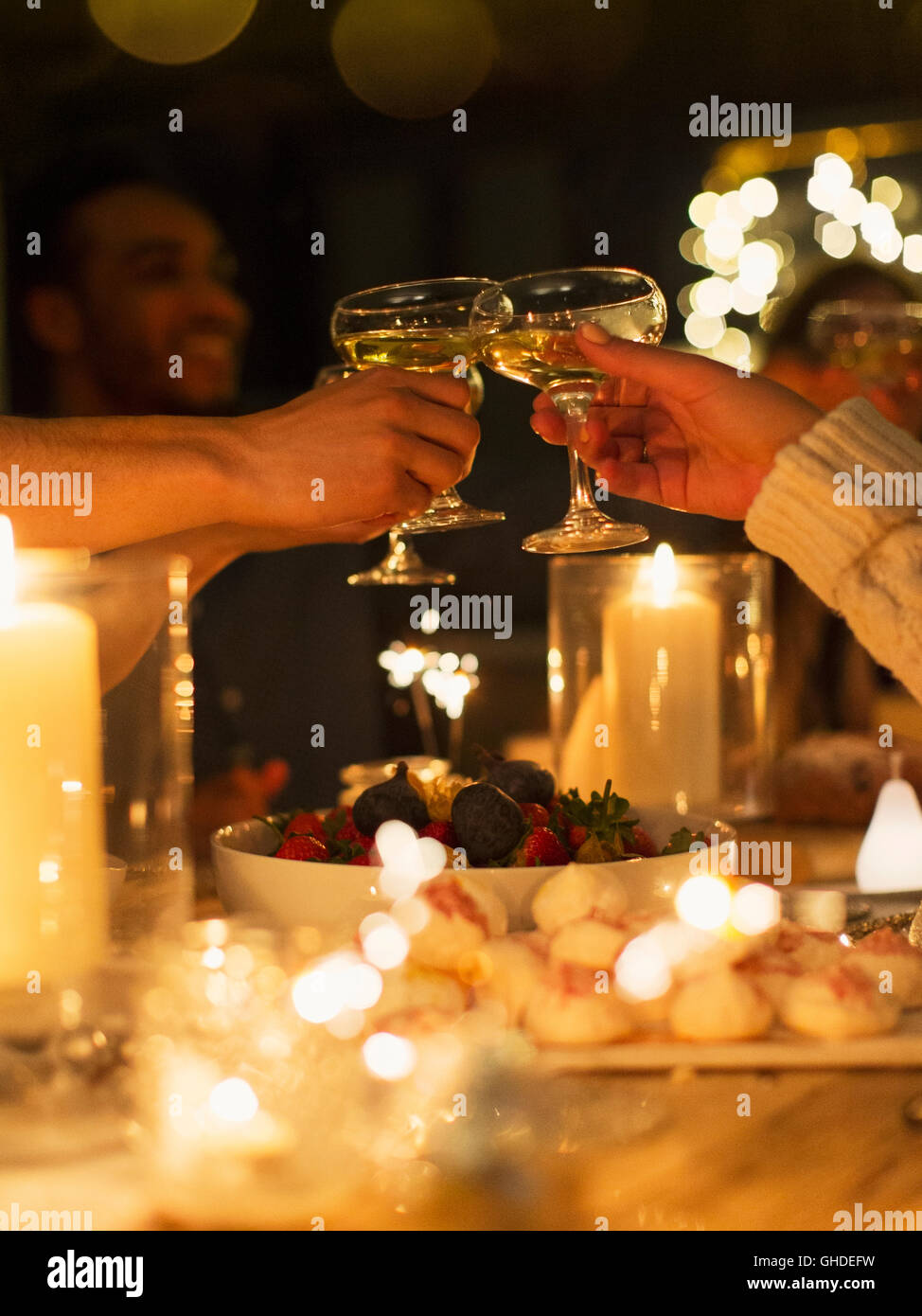 Friends toasting champagne glasses over table at candlelight Christmas dinner Stock Photo