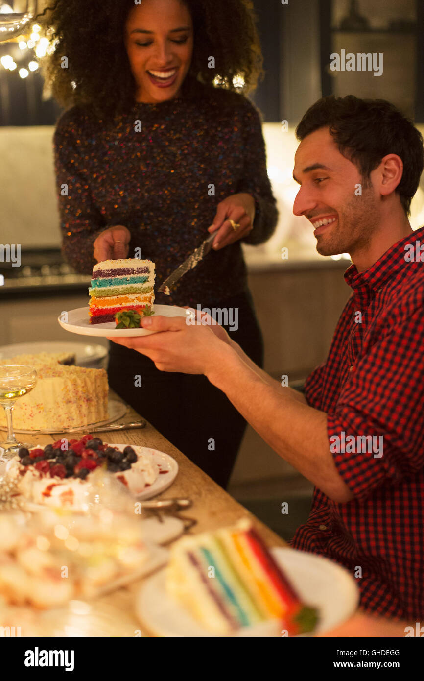 Woman serving layer cake to man at table Stock Photo