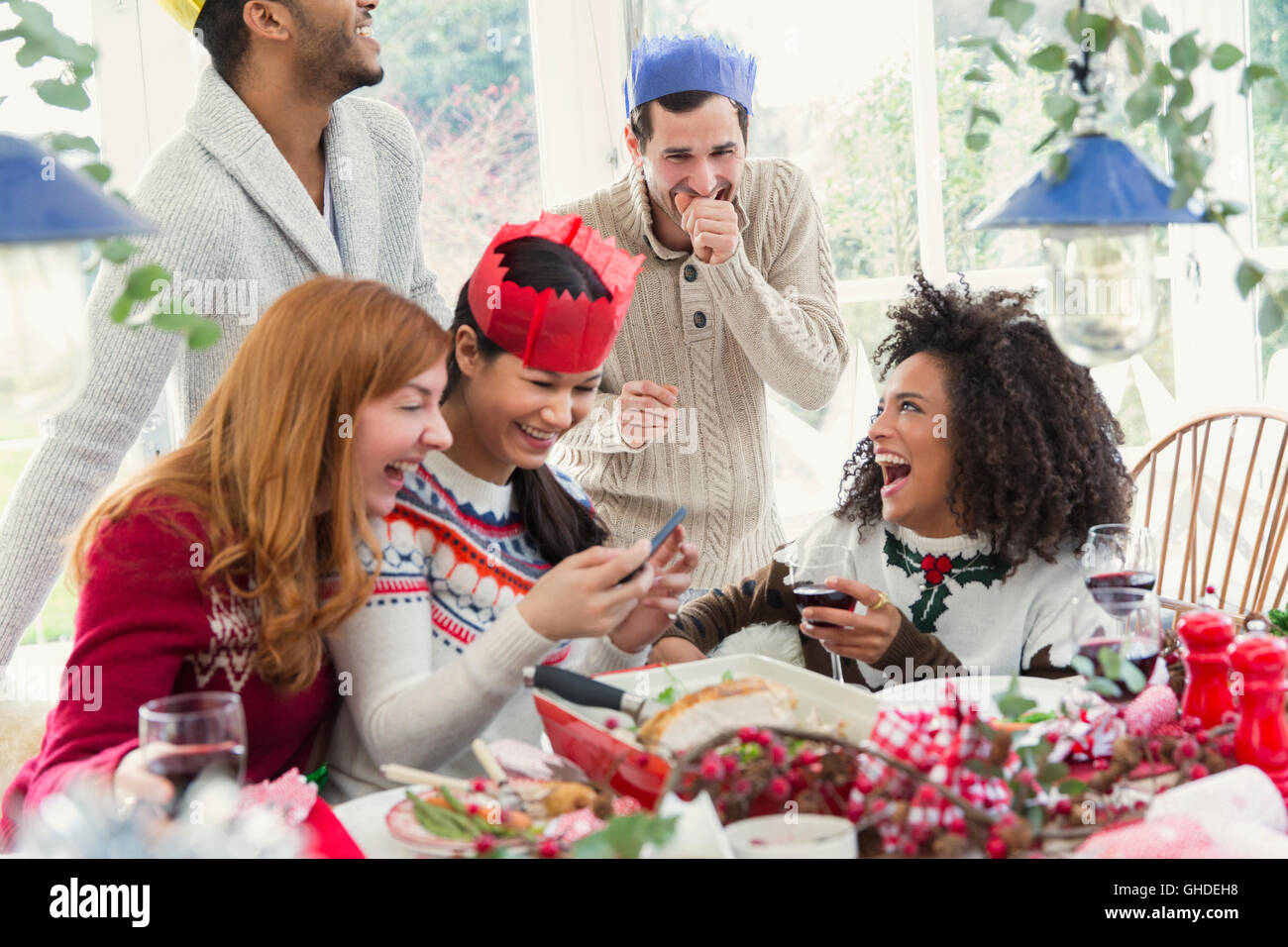 Laughing friends wearing paper crowns at Christmas dinner Stock Photo