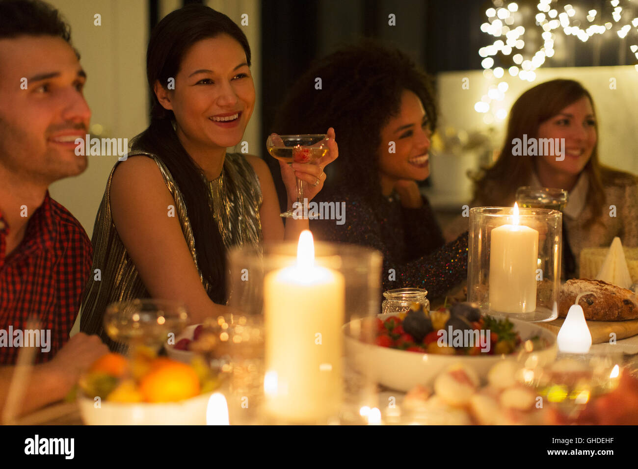 Smiling friends drinking champagne at candlelight Christmas dinner Stock Photo