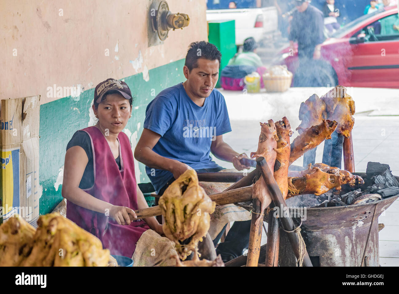 AZUAY, ECUADOR, OCTOBER - 2015 - Couple of chefs cooking traditional roasted cuy at street market in Azuay province, Ecuador. Stock Photo