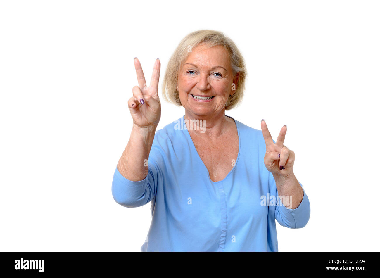 Smiling attractive blond elderly woman giving a double v-sign for peace or victory,upper body isolated on white Stock Photo