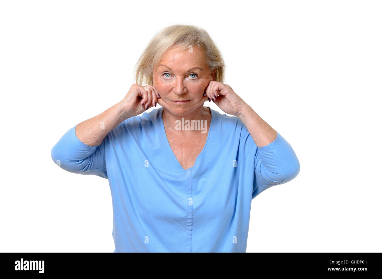 Elderly woman pulling at the skin on her jowls or cheeks pinching it between her fingers showing the ageing process in a beauty  Stock Photo