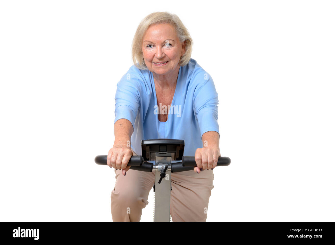 Smiling elderly woman riding an exercise bicycle at a gym or home in a ...