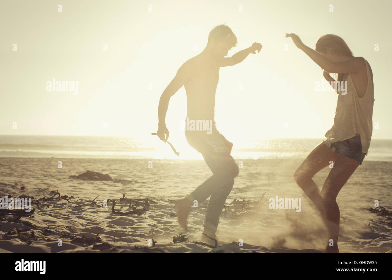Playful couple dancing on sunny beach at sunset Stock Photo