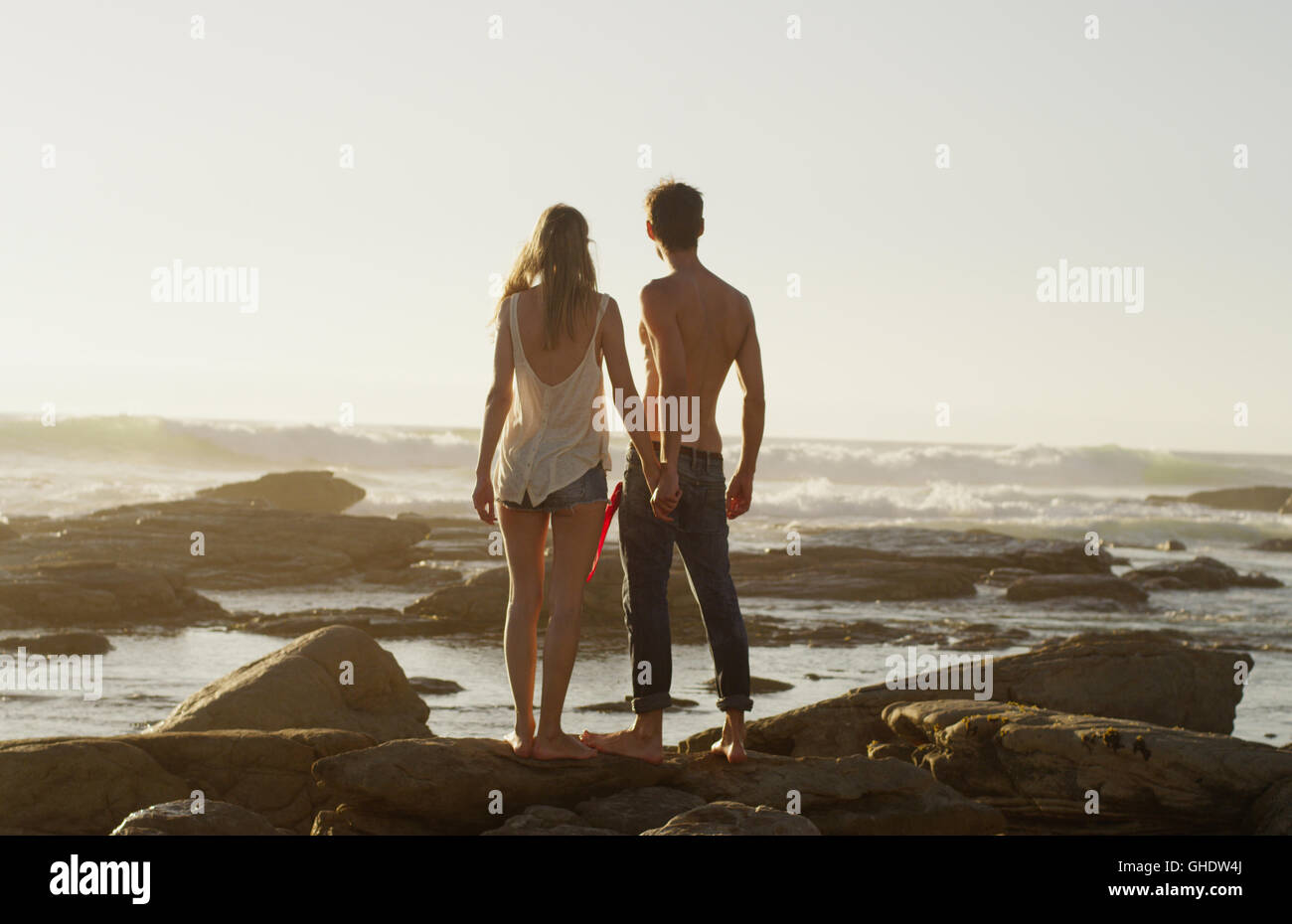 Young couple holding hands and looking at ocean view Stock Photo