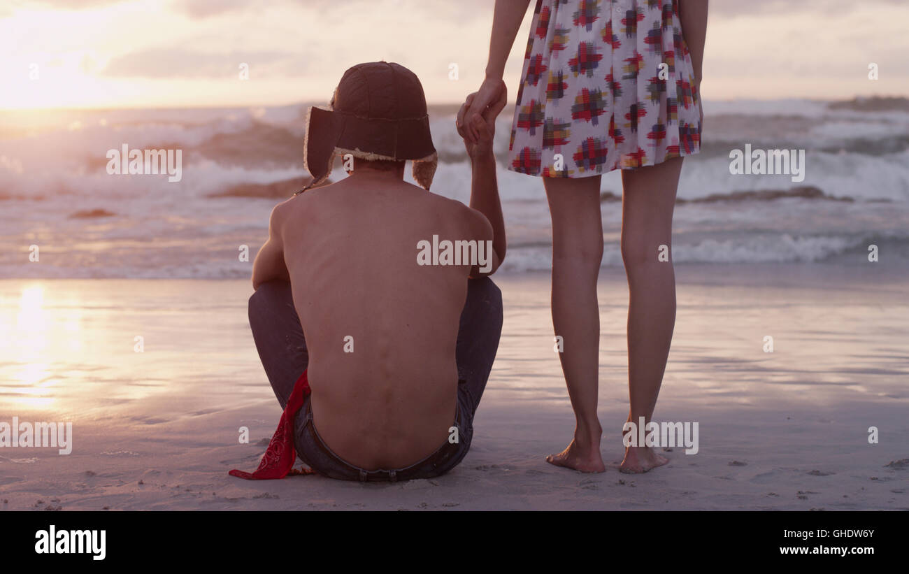 Young couple holding hands on beach at sunset Stock Photo - Alamy