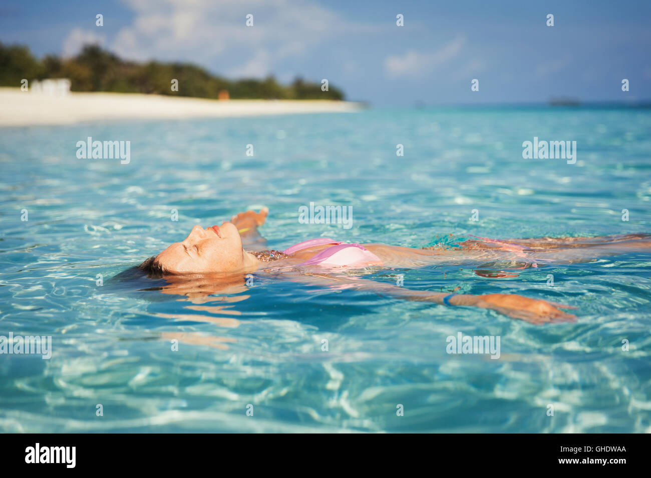 Serene woman floating in tropical ocean Stock Photo