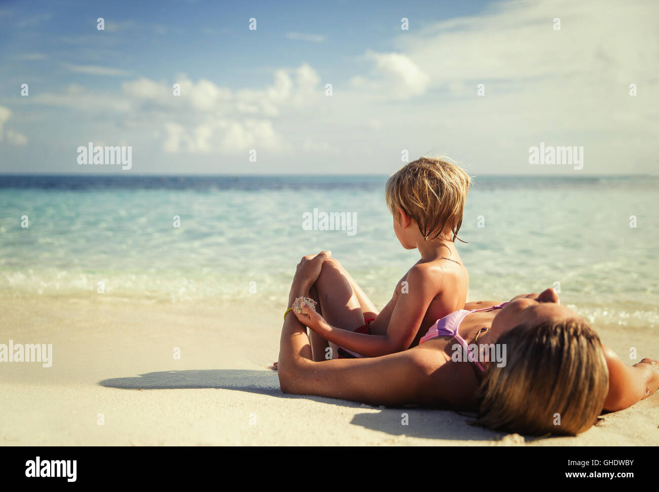 Mother and son laying and relaxing on tropical beach Stock Photo