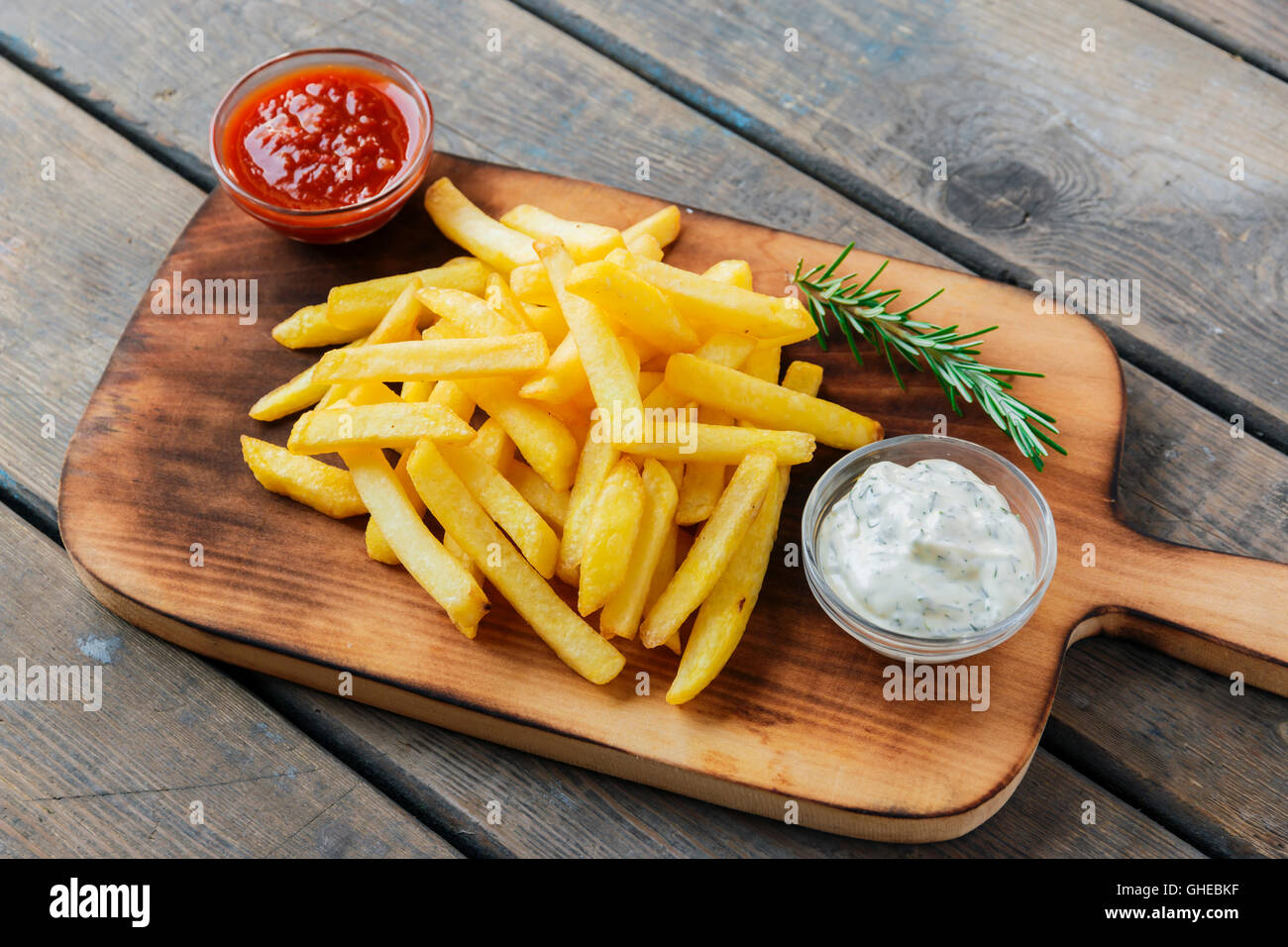 French fries with sauce on a cutting board Stock Photo