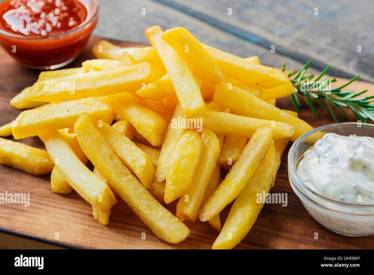 French fries with sauce on a cutting board Stock Photo