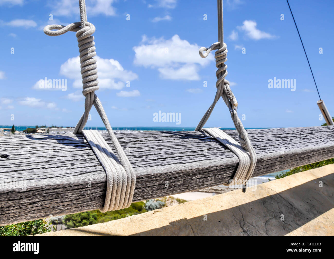 Closeup of knotted lanyard flag rope lines secured to wooden plank railing  with a hint of the Indian Ocean under a blue sky Stock Photo - Alamy