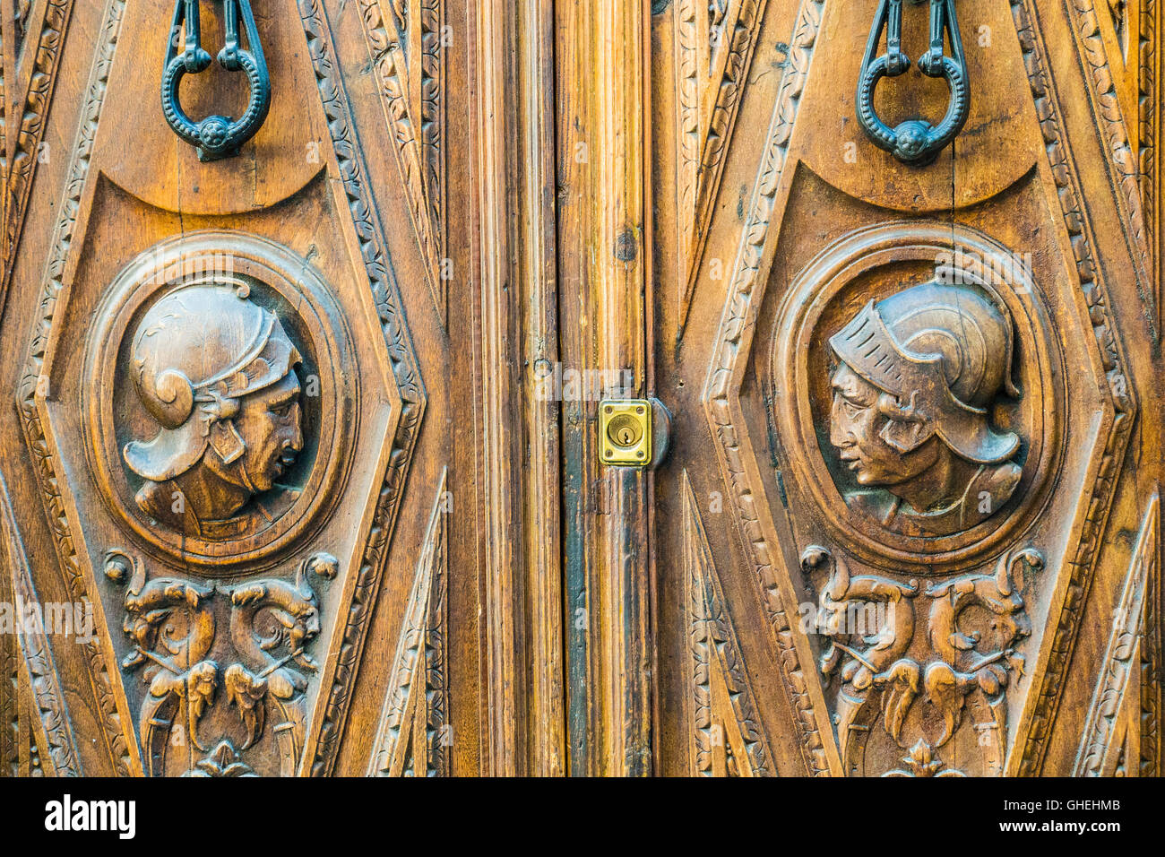 An old Spanish wooden door with the profiles of the heads of Spanish conquistadors in helmets in the Albayzín barrio of Granada. Stock Photo