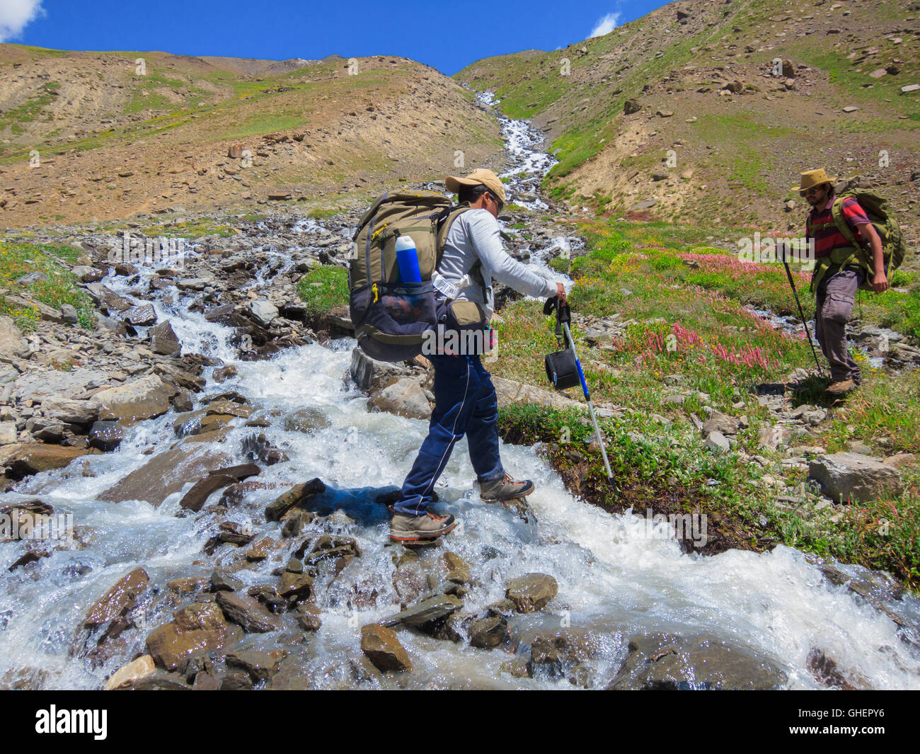 Trekkers crossing a stream - Bhaba Pass trekking trail (Himachal Pradesh, India) Stock Photo