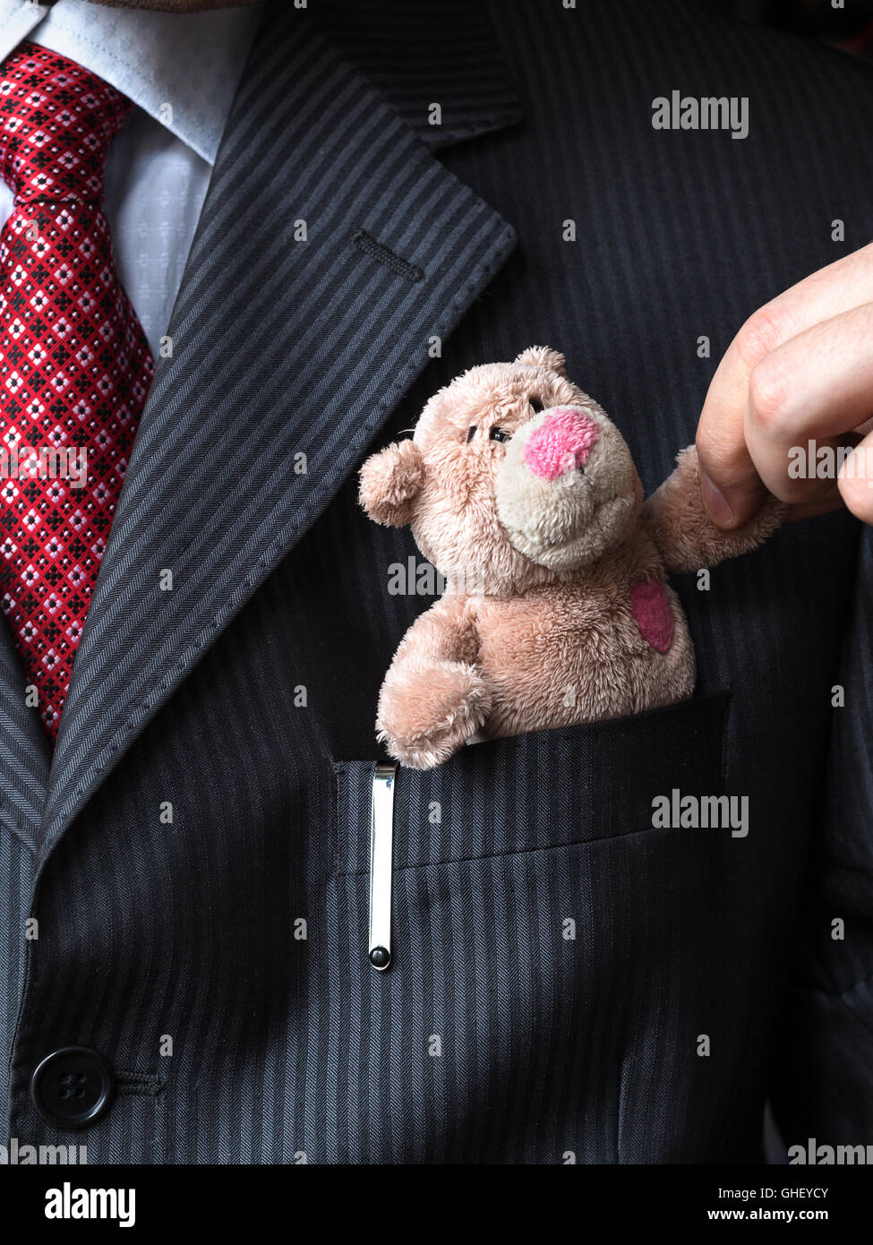 The elegant stylish businessman keeping cute teddy bear in a his breast suit pocket. Formal negotiations concept. Stock Photo