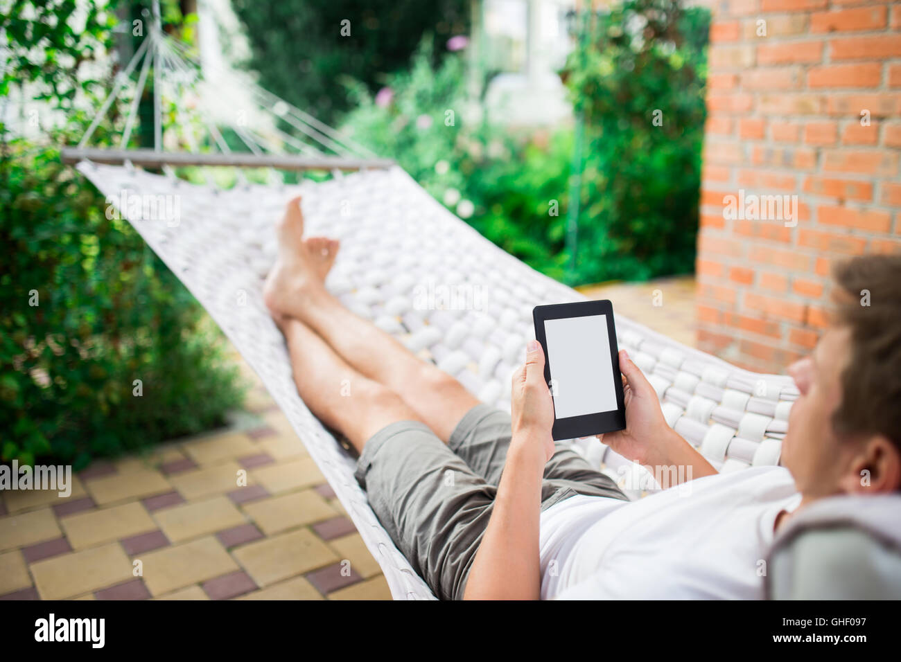 Man using e-book or tablet computer while relaxing in a hammock Stock Photo